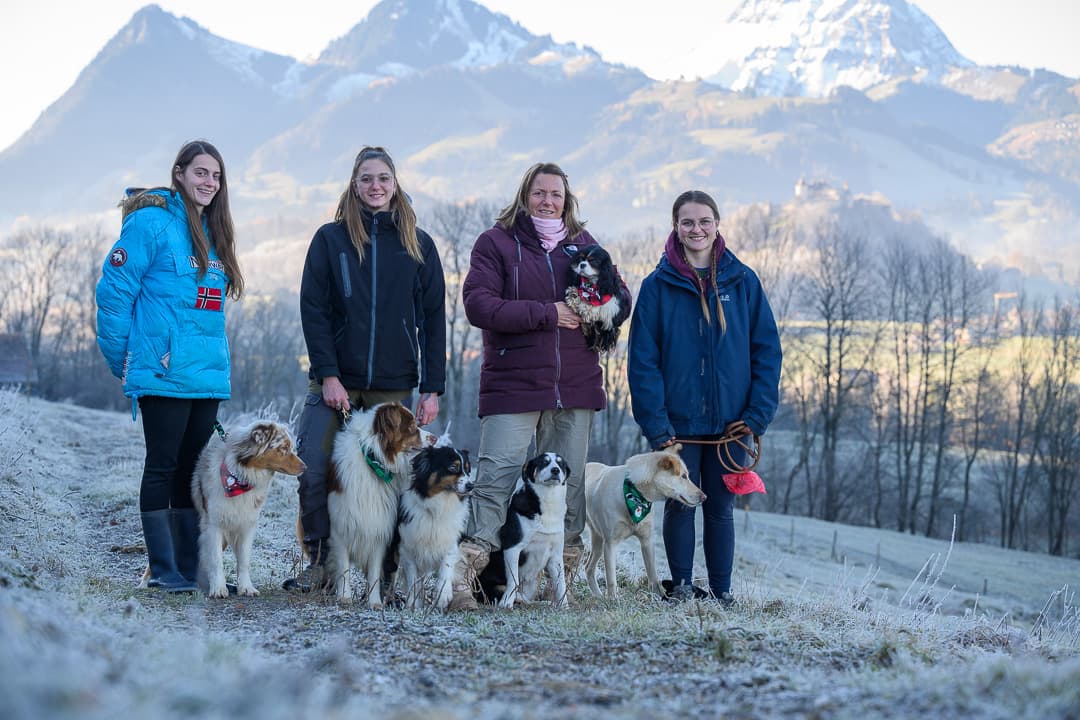 L'équipe de la pension Au Cœur du Loup avec les chiens, montagnes de la Gruyère en arrière-plan